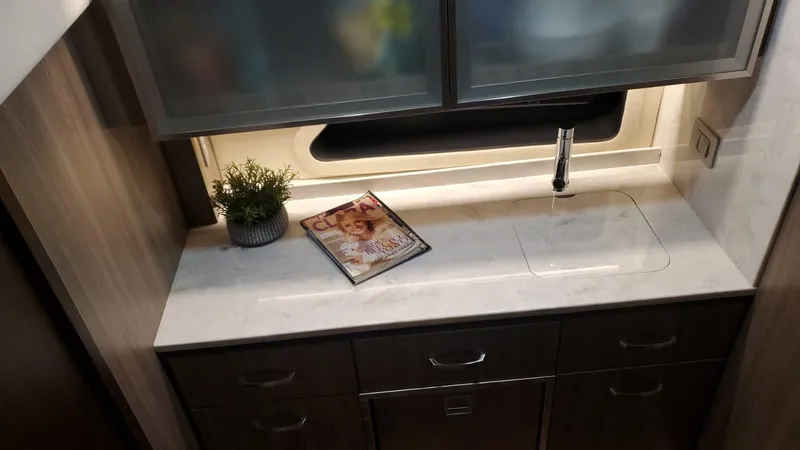 Slide: The Image of Modern kitchen area in 2022 Regal 42 XO yacht with sink, plant, and magazine. - 9