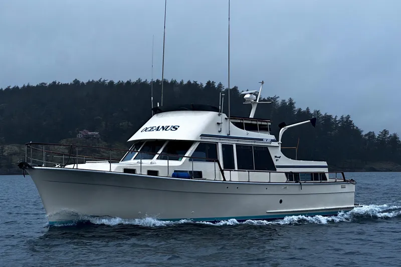 The Image of 1981 Tollycraft 48 Motor Yacht cruising on water with forested shoreline in the background. - 0