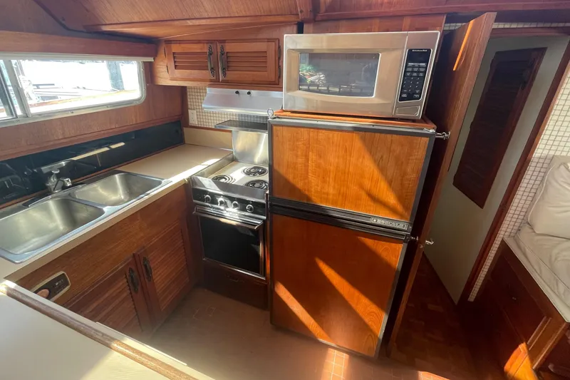 Slide: The Image of 1981 Tollycraft 48 Motor Yacht kitchen with stove, microwave, fridge, and double sink. - 18