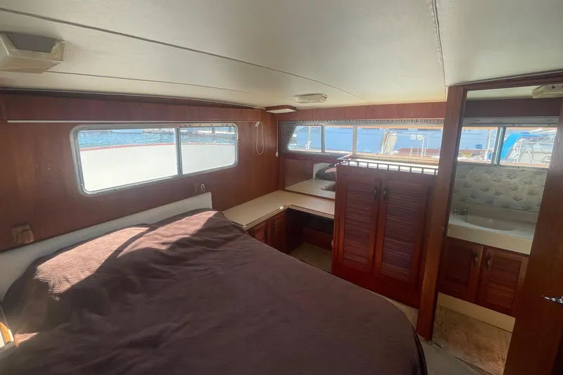 Slide: The Image of 1981 Tollycraft 48 Motor Yacht bedroom with wooden interior and large windows. - 27
