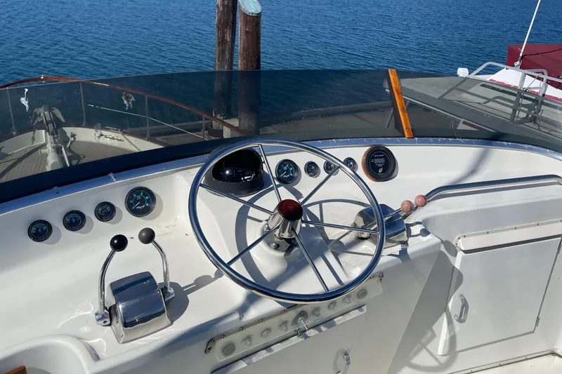 Slide: The Image of 1981 Tollycraft 48 Motor Yacht helm with steering wheel and controls, docked by the water. - 7
