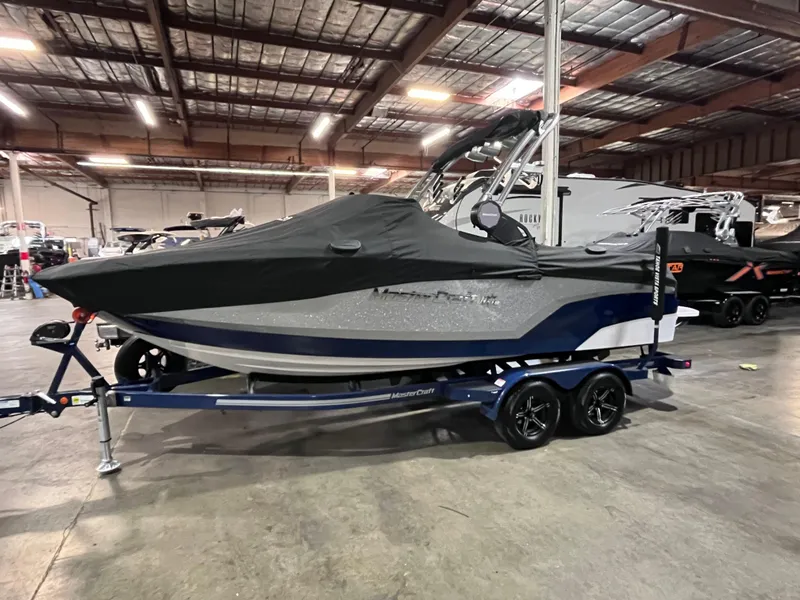 Slide: The Image of 2023 MasterCraft NXT21 boat with cover on trailer in warehouse setting. - 3