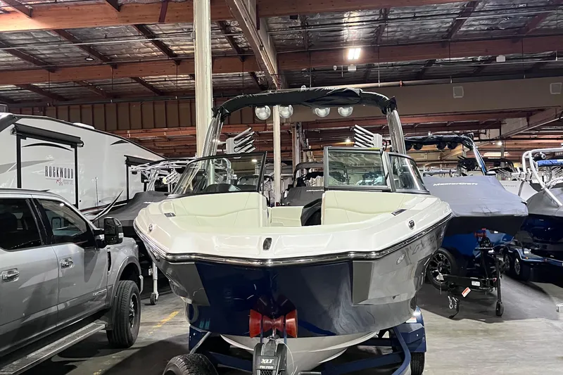 Slide: The Image of 2023 MasterCraft NXT21 boat in showroom, surrounded by vehicles and other boats. - 4