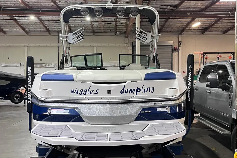 Slide: The Image of 2023 MasterCraft NXT21 boat in a warehouse, featuring "wiggles dumpling" text on the back. - 5
