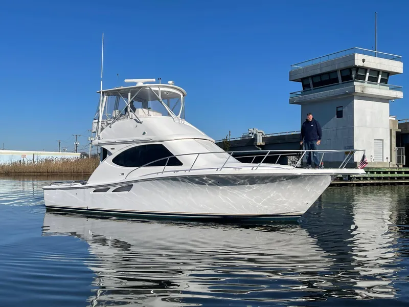 Slide: The Image of 2008 Tiara Yachts 3900 Convertible boat docked near a modern building. - 2
