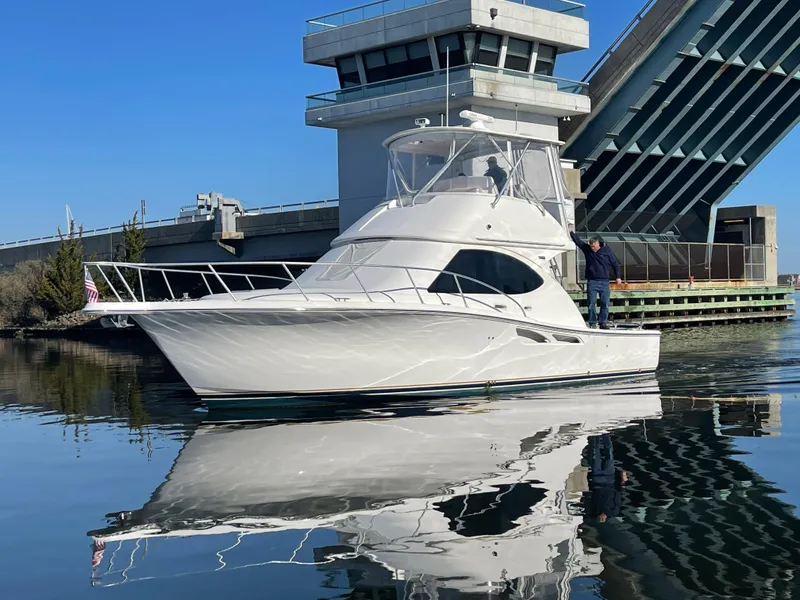 Slide: The Image of 2008 Tiara Yachts 3900 Convertible boat near a bridge on calm water. - 4