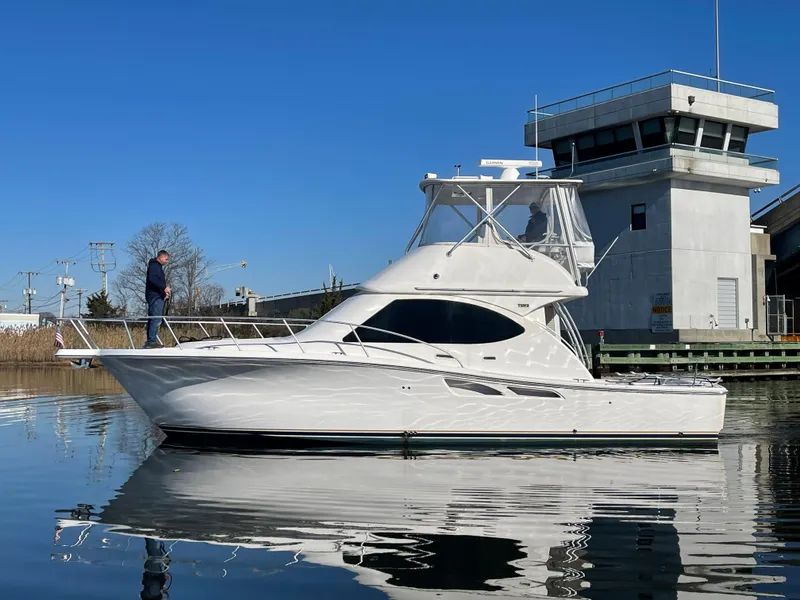 Slide: The Image of 2008 Tiara Yachts 3900 Convertible on calm water near a dock. - 6