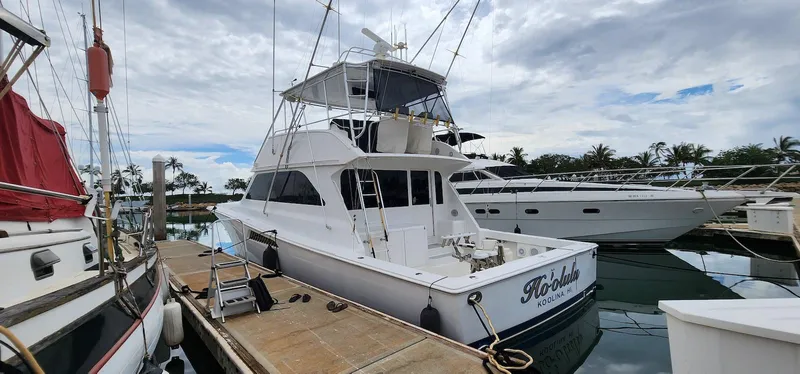 The Image of 2000 Viking 55 Convertible yacht docked at marina under cloudy sky. - 1