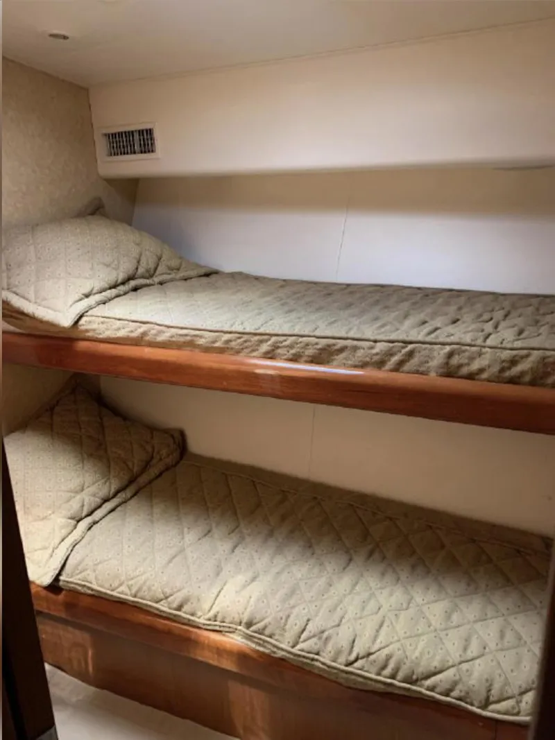 Slide: The Image of Bunk beds in 2000 Viking 55 Convertible yacht cabin, featuring wooden frames and beige bedding. - 17