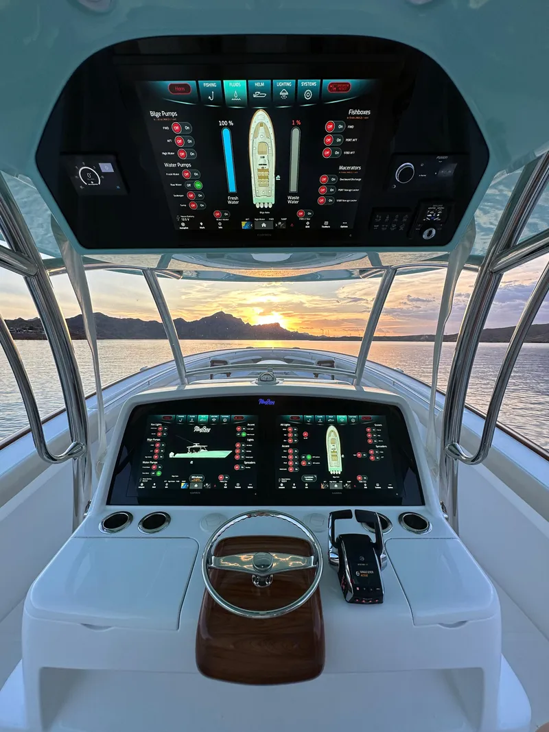 Slide: The Image of 2025 Mag Bay 43 Center Console boat dashboard with advanced navigation screens at sunset. - 20