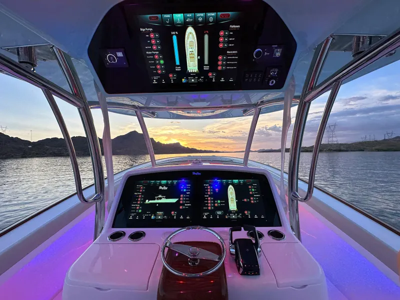 Slide: The Image of 2025 Mag Bay 43 Center Console boat cockpit with advanced navigation screens at sunset. - 21