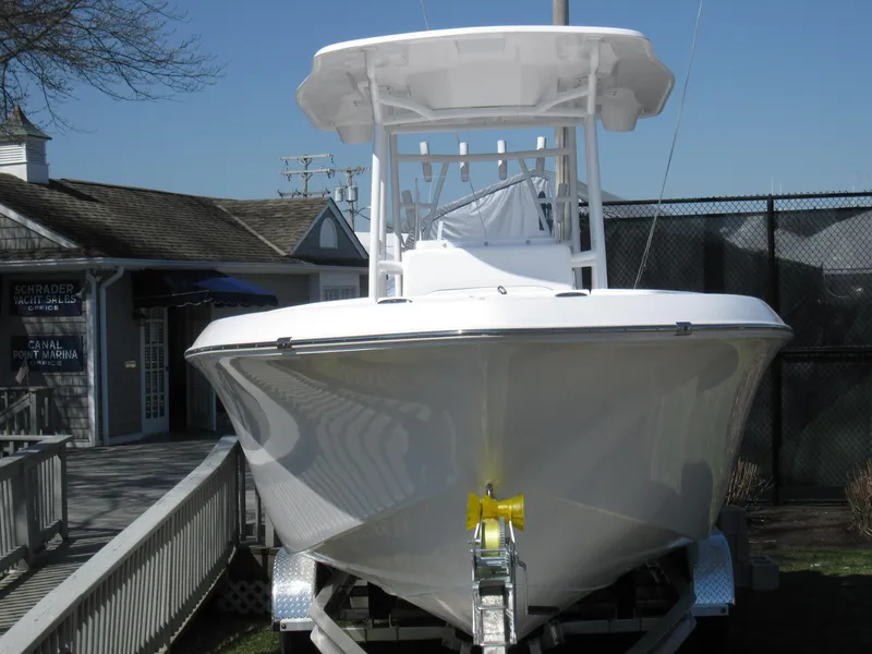 Slide: The Image of 2023 Clearwater 2300 boat on trailer, front view, docked near a building. - 3