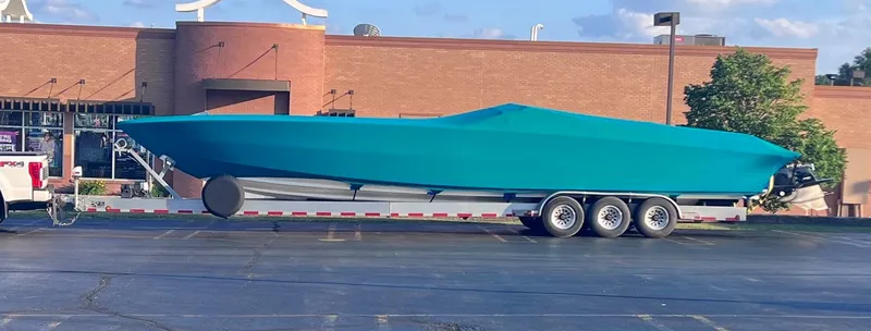 Slide: The Image of 1994 Apache 41 boat on a trailer, covered in blue tarp, parked in a lot. - 12