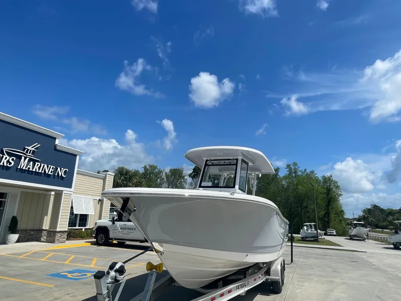 Slide: The Image of 2023 Robalo 270 boat on trailer at dealership under clear blue sky. - 4