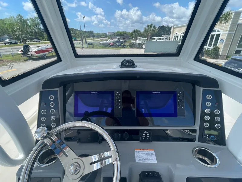 Slide: The Image of 2023 Robalo 270 boat dashboard with dual Simrad displays and steering wheel. - 17