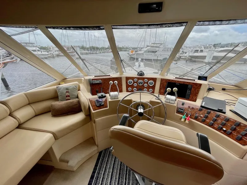 Slide: The Image of 2004 Meridian 490 Pilothouse interior with helm, steering wheel, and marina view. - 19