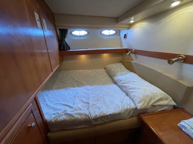 Slide: The Image of Cozy bedroom in 2004 Meridian 490 Pilothouse yacht with wood accents and porthole windows. - 38