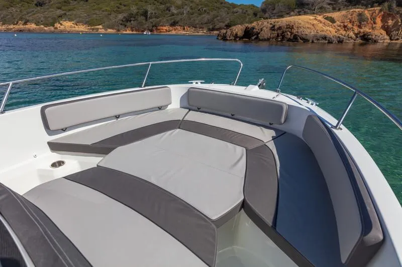 Slide: The Image of 2023 Jeanneau Leader 6.5 CC S3 boat with cushioned seating in a scenic coastal area. - 3