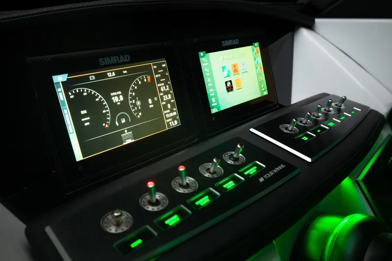 Slide: The Image of 2023 Four Winns H2 boat dashboard with Simrad displays and illuminated control switches. - 46