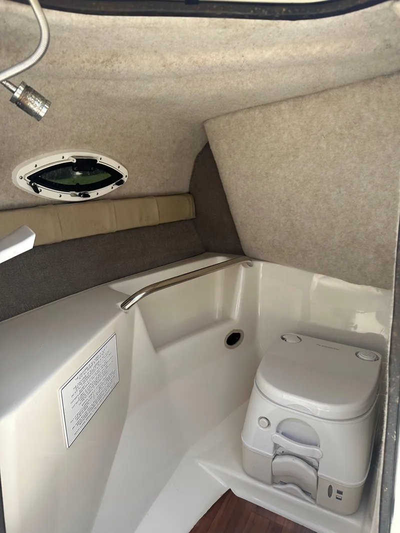 Slide: The Image of 2018 Stingray 214 LR boat interior with compact toilet and porthole. - 10