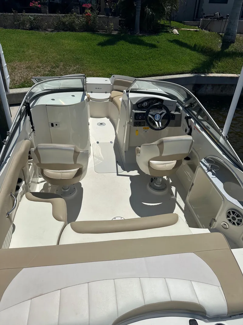 Slide: The Image of 2018 Stingray 214 LR boat interior with beige seating and steering console. - 6
