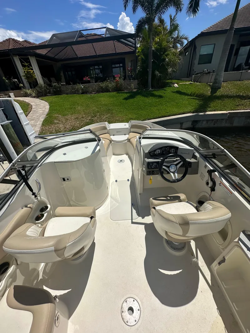 Slide: The Image of 2018 Stingray 214 LR boat interior with steering wheel, seating, and waterfront view. - 8