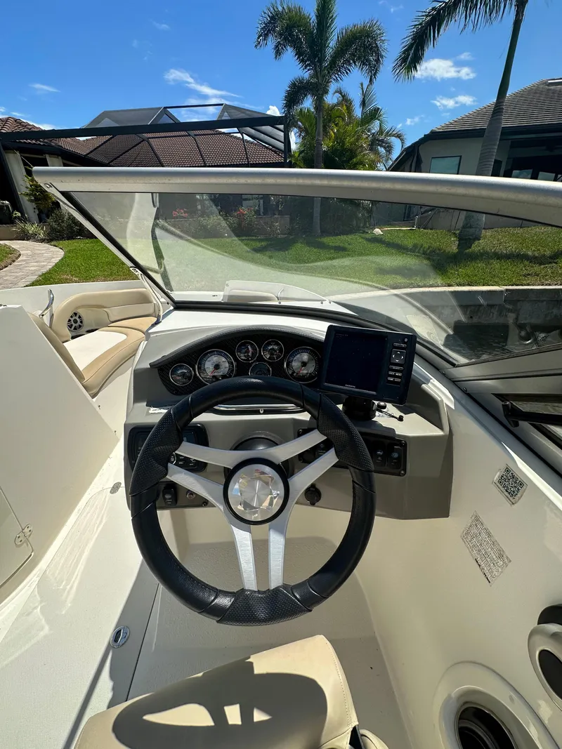 Slide: The Image of 2018 Stingray 214 LR boat cockpit with steering wheel and dashboard, under clear blue sky. - 9