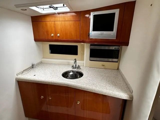 Slide: The Image of 2005 Cranchi 37 Smeraldo yacht kitchen with wood cabinets, sink, and microwave. - 24