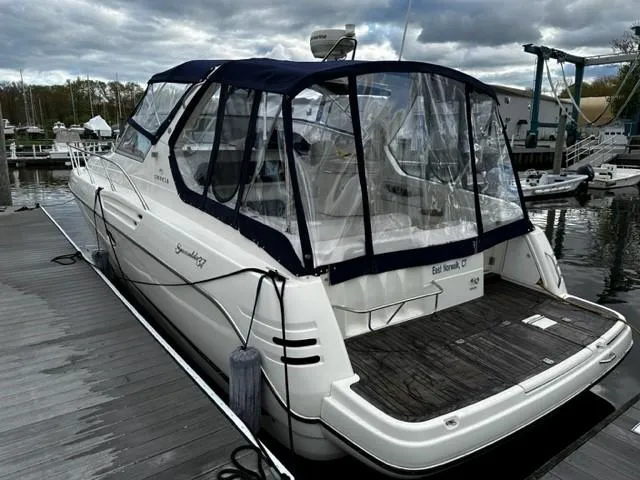 Slide: The Image of 2005 Cranchi 37 Smeraldo yacht docked, featuring a blue canopy and spacious deck. - 5