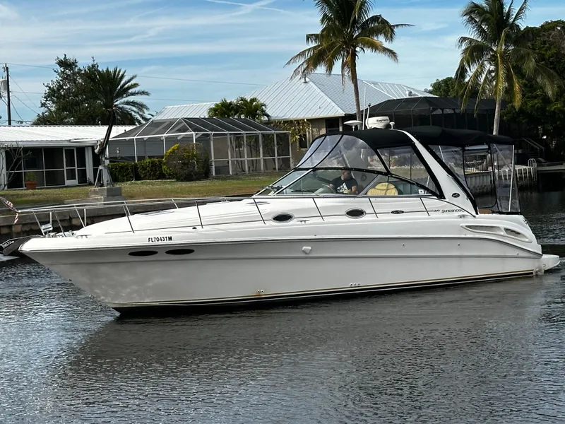 Slide: The Image of 2001 Sea Ray 340 Sundancer yacht cruising on a calm waterway with palm trees in the background. - 2