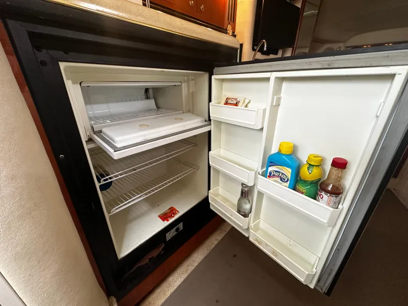 Slide: The Image of Open refrigerator inside a 2001 Sea Ray 340 Sundancer boat, showing shelves and door compartments. - 38