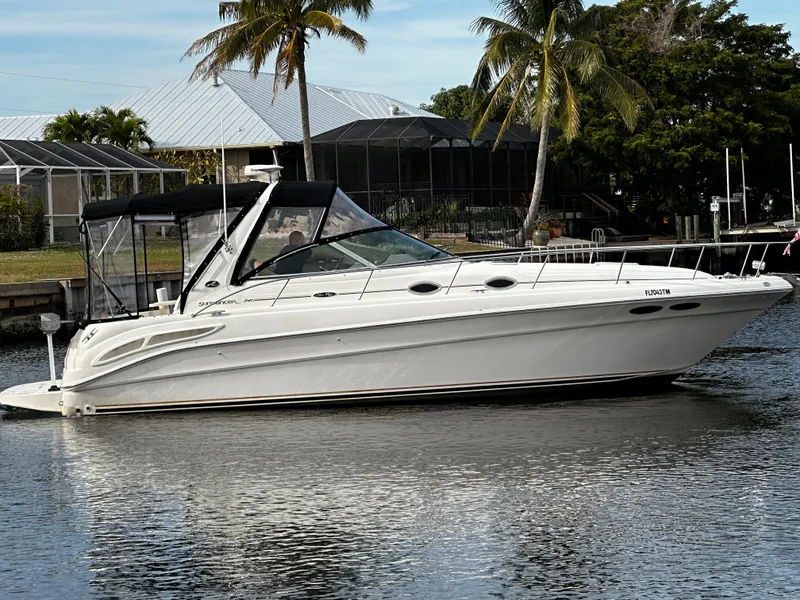 Slide: The Image of 2001 Sea Ray 340 Sundancer boat docked near palm trees and waterfront homes. - 8