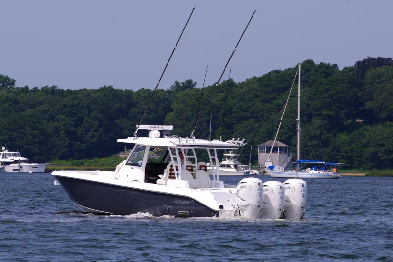 Slide: The Image of 2024 Everglades 395 Center Console boat cruising on a lake with trees in the background. - 10