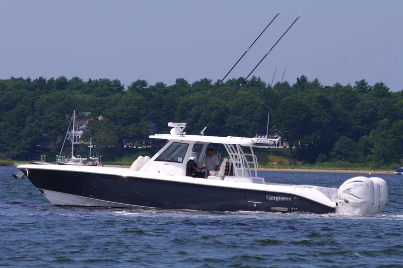 Slide: The Image of 2024 Everglades 395 Center Console boat cruising on a lake with forested shoreline. - 11