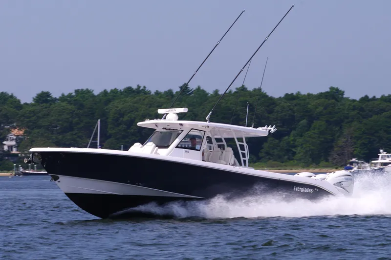Slide: The Image of 2024 Everglades 395 Center Console boat cruising on water, forested shoreline in background. - 2
