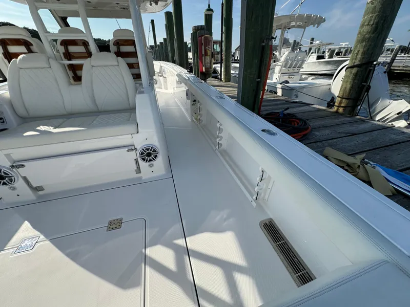Slide: The Image of 2024 Everglades 395 Center Console boat interior at marina, featuring white seating and deck. - 31