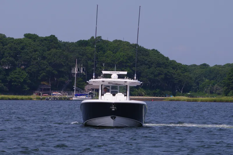 Slide: The Image of 2024 Everglades 395 Center Console boat cruising on a lake with forested shoreline. - 5