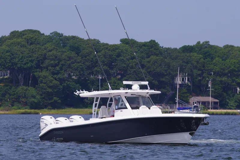 Slide: The Image of 2024 Everglades 395 Center Console boat cruising on a lake with lush green trees. - 6