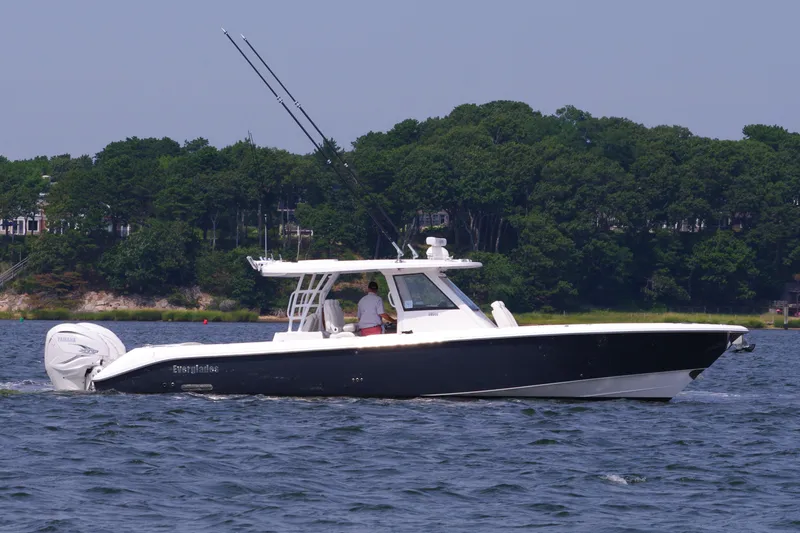 Slide: The Image of 2024 Everglades 395 Center Console boat cruising on a lake with forested shoreline. - 7