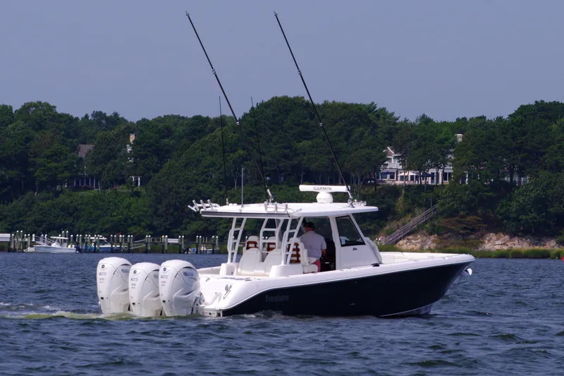 Slide: The Image of 2024 Everglades 395 Center Console boat cruising on a lake with scenic background. - 8