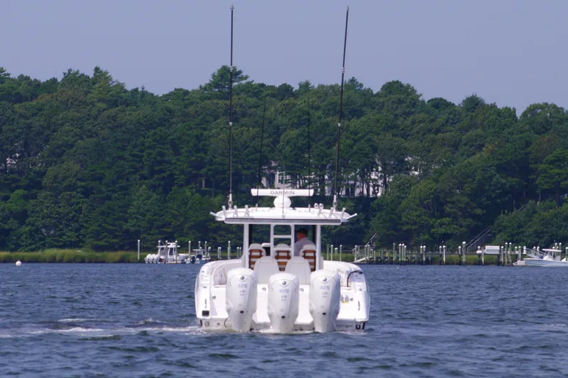Slide: The Image of 2024 Everglades 395 Center Console boat cruising on a lake with forested shoreline. - 9
