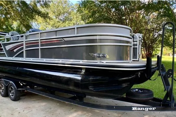 The Image of 2023 Ranger Reata 220C pontoon boat on trailer, parked outdoors. - 0