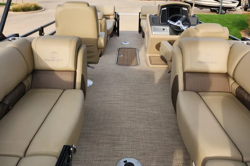 Slide: The Image of 2023 Regency 230 LE3 boat interior with beige seating and steering console. - 2
