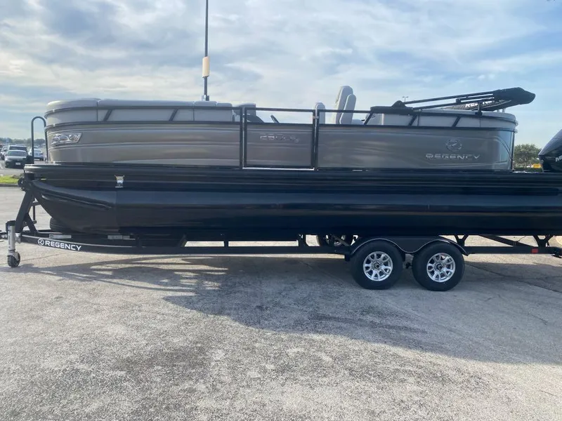 Slide: The Image of 2023 Regency 230 LE3 pontoon boat on a trailer in a parking lot. - 1