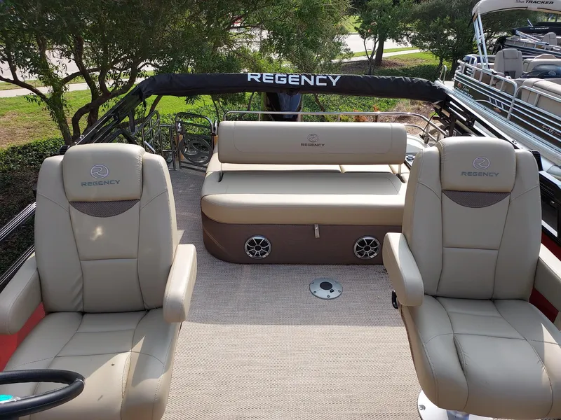 Slide: The Image of 2023 Regency 230 LE3 Sport boat interior with beige seating and steering wheel. - 4
