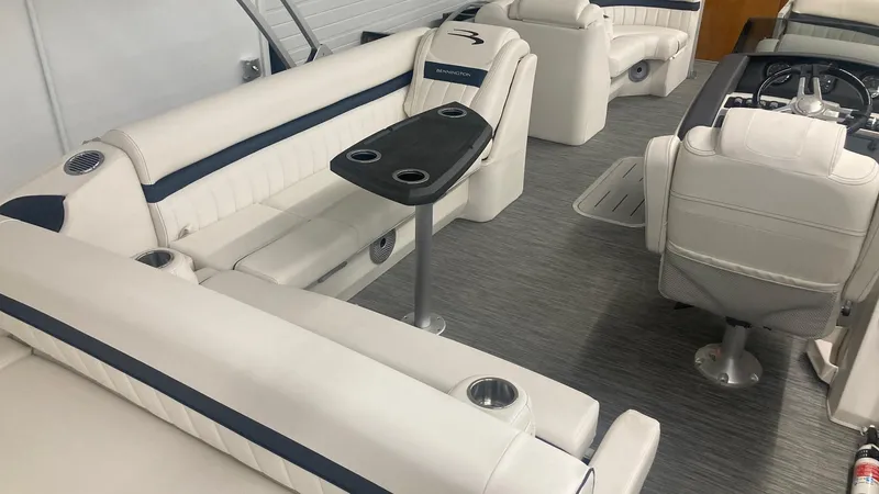 Slide: The Image of 2023 Bennington 24 LXSB boat interior with white and blue seating, table, and steering console. - 6