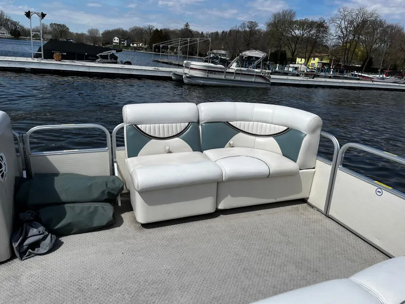 Slide: The Image of 2008 Sweetwater SW2186RE4 pontoon boat interior with white seating by a lake dock. - 6