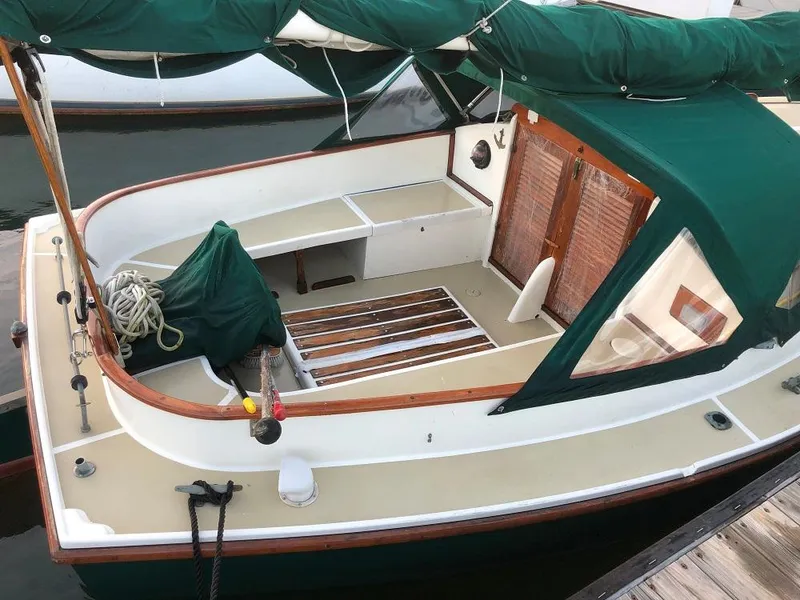 Slide: The Image of 1977 Marshall 22 sailboat with green canopy and wooden accents docked at marina. - 10