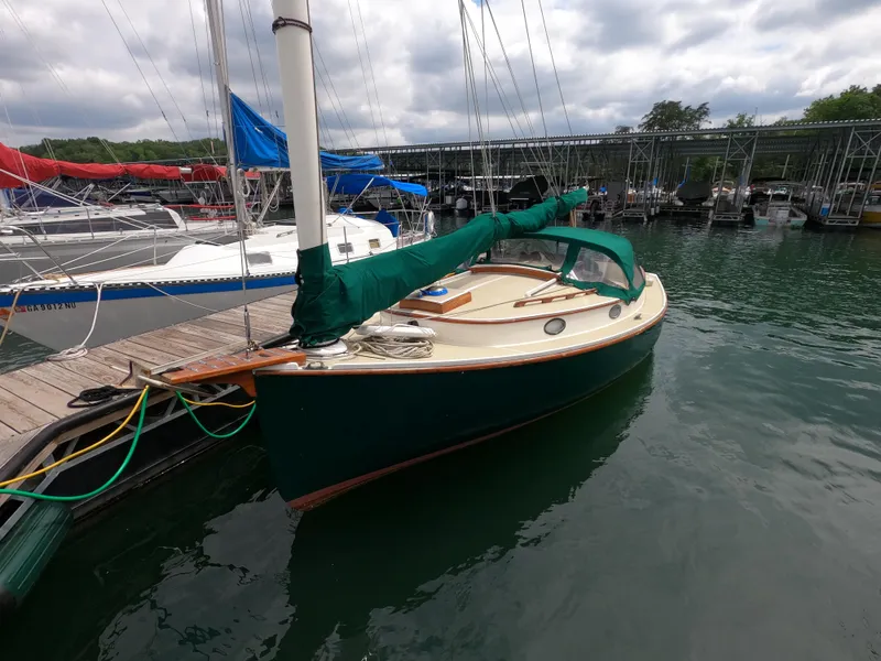 Slide: The Image of 1977 Marshall 22 sailboat docked at marina with green cover and calm water. - 12