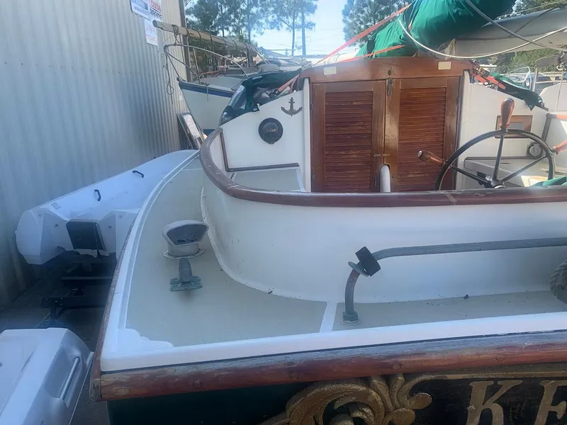 Slide: The Image of 1977 Marshall 22 sailboat with wooden accents and green sail, docked near other boats. - 14